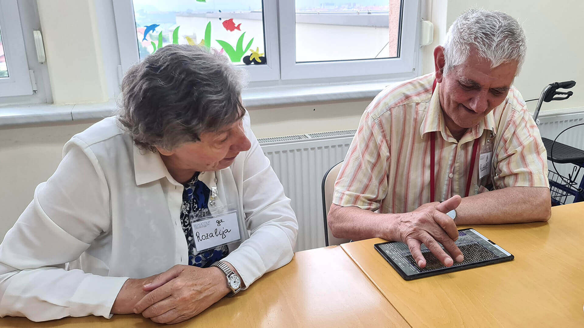 tecnhician watching elderly citizen trying new technology in retirement home at Dom Danice Vogrinec Maribor